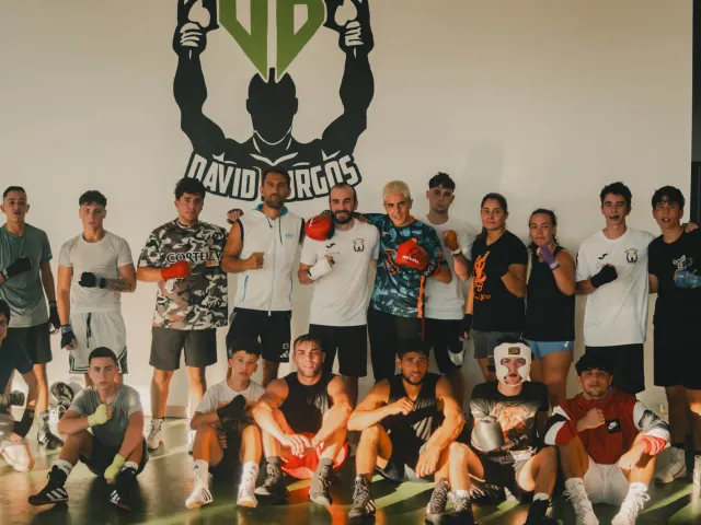 Grupo del Club de Boxeo David Burgos posando bajo el logo del club