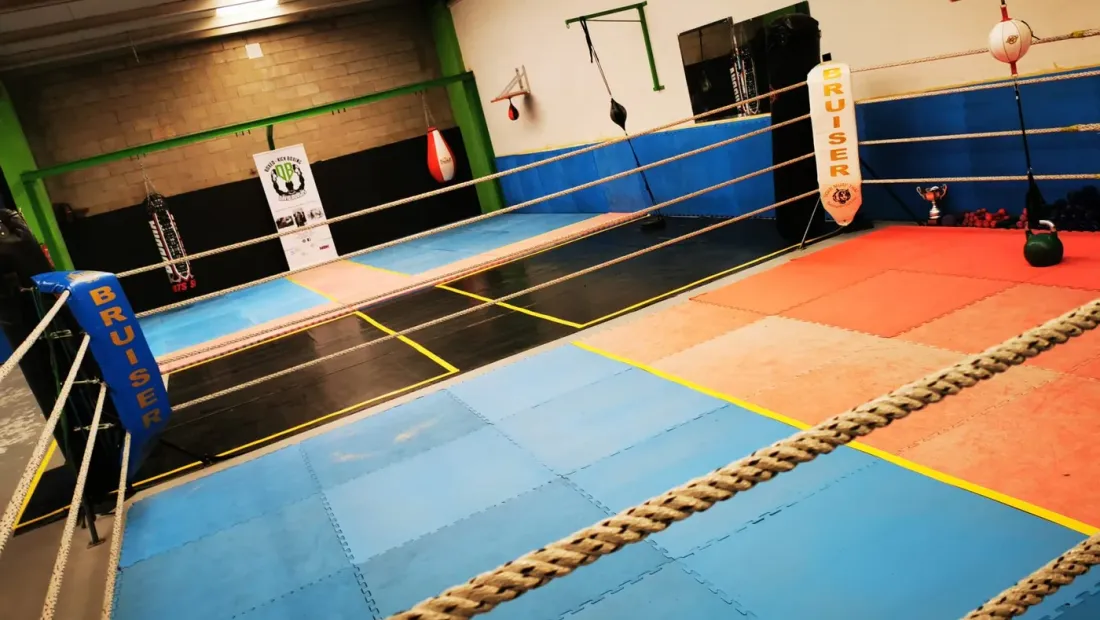 Sala de entrenamiento del club con el ring montado y los sacos colgados, lista para la vuelta a las clases presenciales