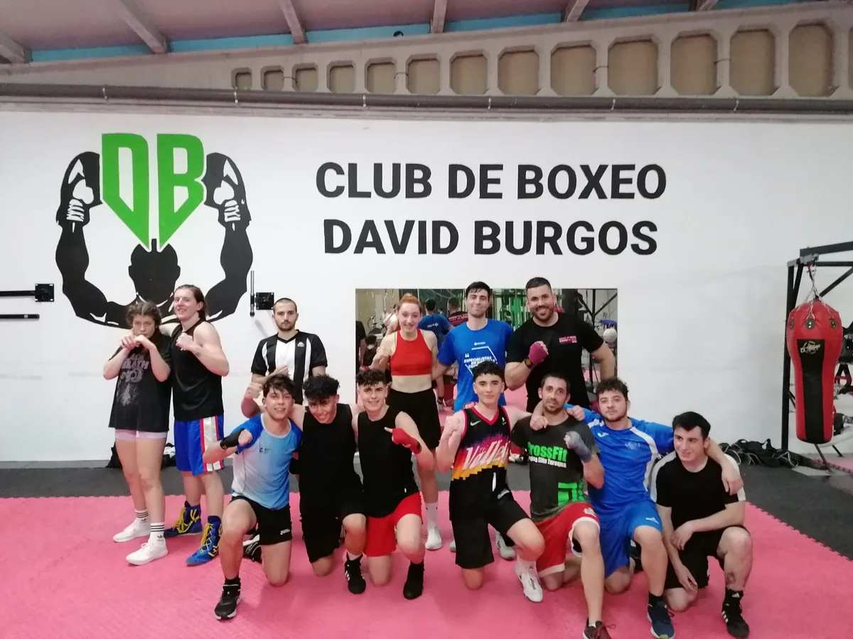 Atletas del club posando juntos, de pie y agachados, bajo el logo y el rótulo del Club de Boxeo David Burgos